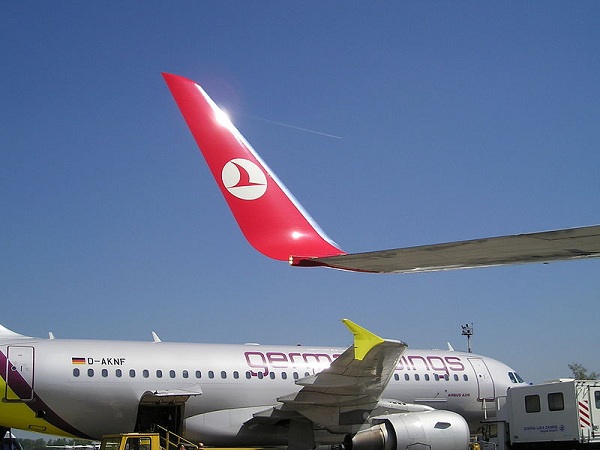  En primer plano, un blended winglet rojo se extiende desde la punta alar de un Boeing 737-800. Al fondo, se aprecia un wingtip fence en el ala derecha de un Airbus A319.